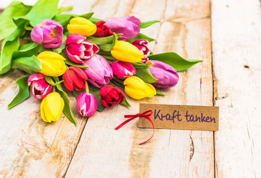 Multicolored tulips arrangement with gift card with german text, Kraft tanken, means relaxation