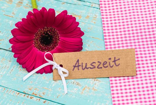 Pink gerbera flower with label and german word, Auszeit, means timeout