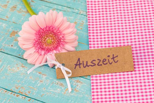 Pink flower with tag and german word, Auszeit, means timeout 