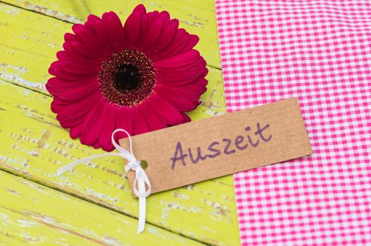Pink flower with tag and german word, Auszeit, means timeout