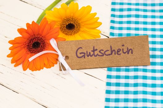 Yellow and orange flower gift with tag with german word, Gutschein, means voucher or coupon