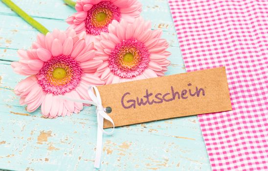 Bunch of pink flowers gift with label with german word, Gutschein, means voucher or coupon