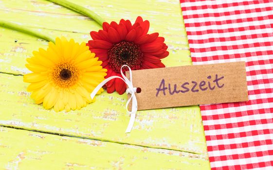 Yellow and red gerbera flowers and label with german word, Auszeit, means timeout