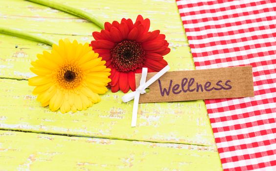 Yellow and red flowers with tag with the word wellness as gift card