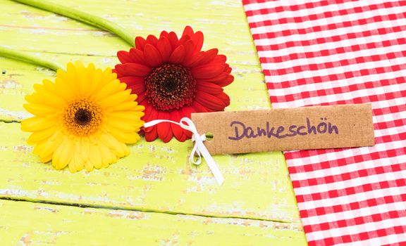 Red and yellow gerbera flowers with card with german word, Dankeschoen, means thanks