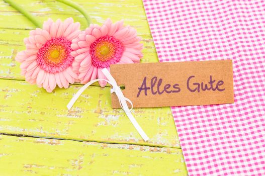 Pink gerbera flowers and card with german text, Alles Gute, means best wishes