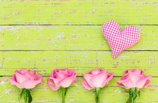 Little pink heart with beautiful rose flowers on colored wood with space for text