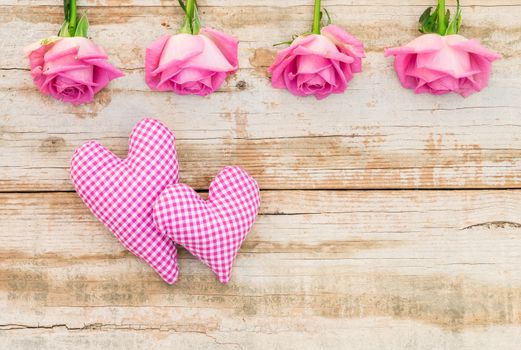 Love background with romantic pink rose flowers and two hearts on vintage wood with copy space