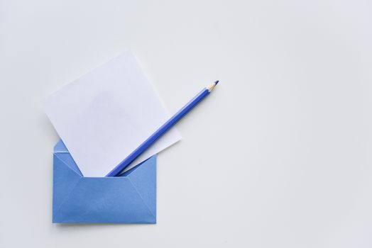 selective focus, white paper sheet and dark blue pencil out of the blue envelope