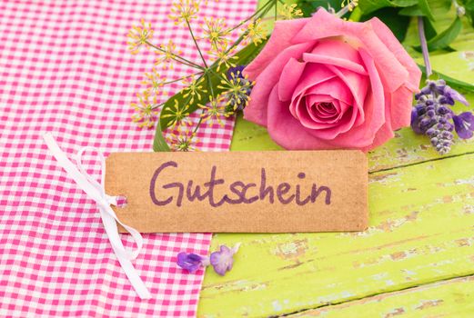 Romantic bouquet of rose flower and card with german word, Gutschein, means voucher or coupon