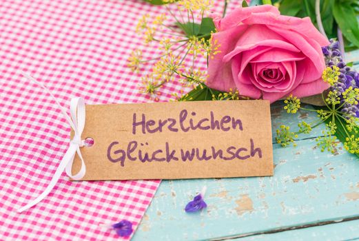 Romantic bunch of flowers and card with german text, Herzlichen Glueckwunsch, means congratulation