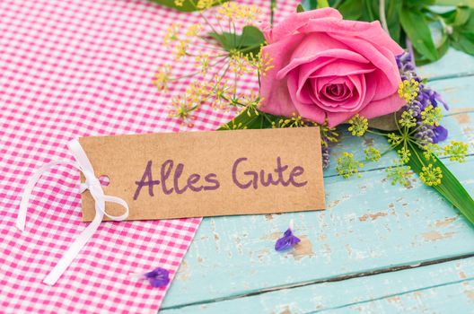 Bouquet of flowers and card with german text, Alles Gute, means best wishes