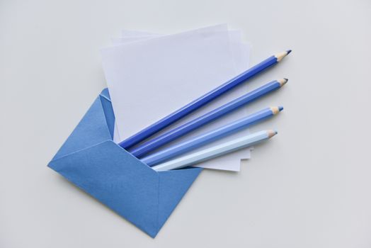 selective focus, four blue pencils and white papers out of the blue envelope