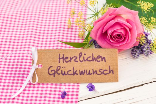 Romantic bunch of flowers and card with german text, Herzlichen Glueckwunsch, means congratulation