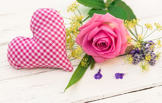 Bunch of flowers with pink rose and romantic heart on white wood, close-up