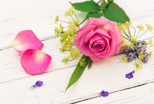 Pink rose flower arrangement, close up, on white wooden background