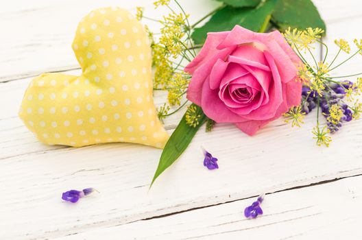 Little yellow fabric heart with romantic flowers on white wooden background