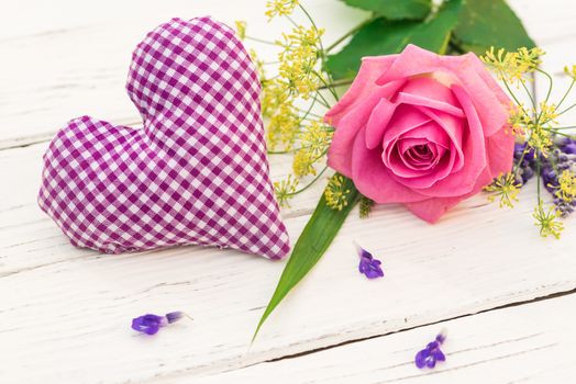 Beautiful bunch of flowers with pink rose and lilac fabric heart on white background