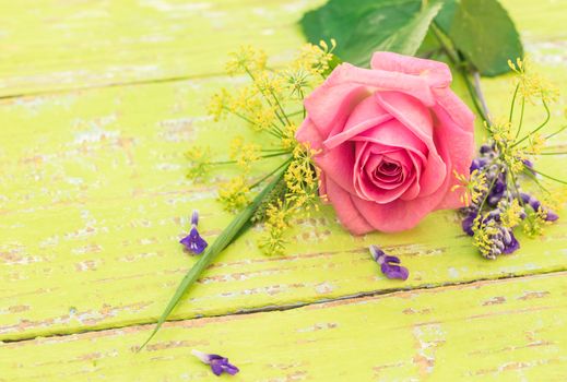 Fresh bunch of flowers with pink rose on yellow wood with space for text