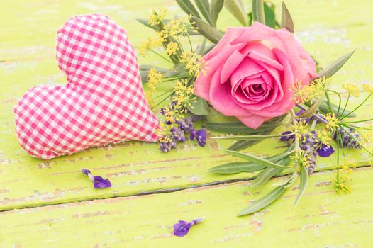 Pink fabric heart with beautiful rose flowers on yellow wooden background