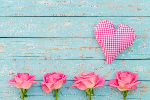 Love background with pink roses and romantic fabric heart on turquoise wood with copy space