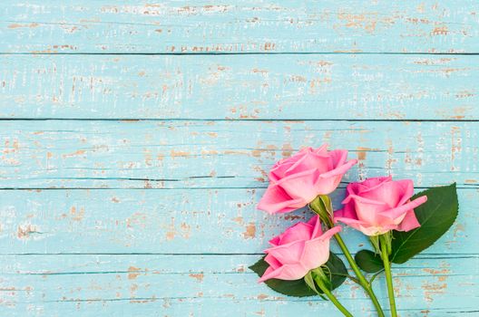 Pink roses bouquet on turquoise wood background with copy space