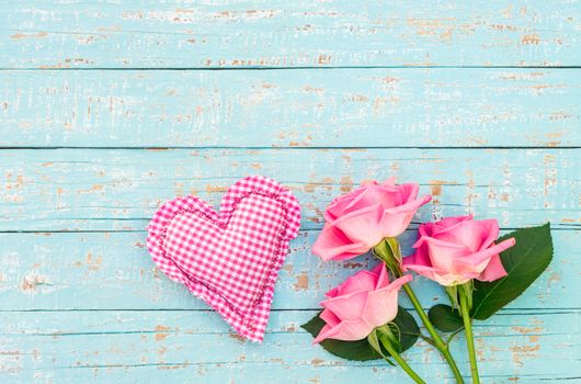 Romantic pink heart with bouquet of roses on light blue wooden background with copy space