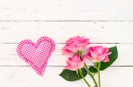 Pink heart with rose flowers on white wooden background with copy space