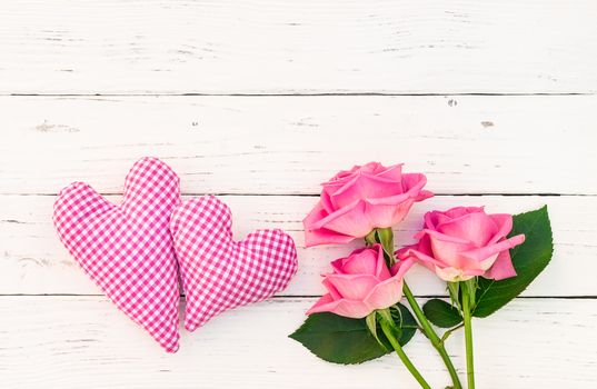 Bunch of pink roses with two love hearts on white wooden background with copy space