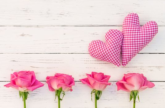 Two pink hearts and roses frame on white wooden background with copy space