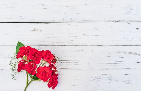 Romantic bunch of red roses on white wood with copy space