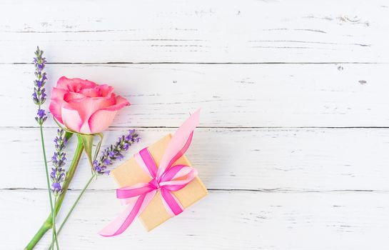 Beautiful bunch of flowers with present on white wooden table, top view with copy space