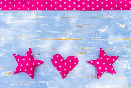 Frame with pink stars and heart on blue wooden background with copy space