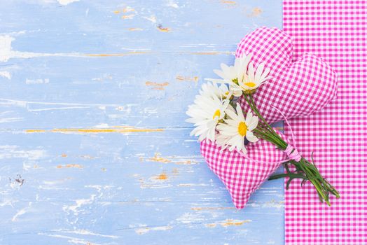 Two love hearts with romantic flowers on blue wood with copy space