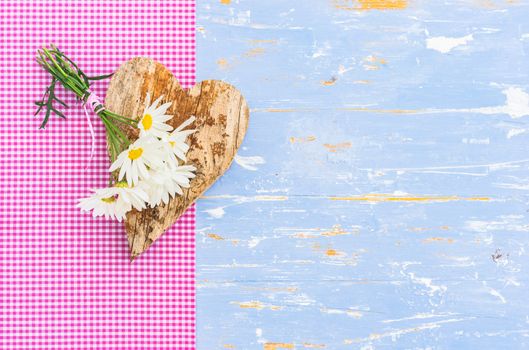 Romantic background with heart and bunch of daisy flowers on blue wooden background with copy space
