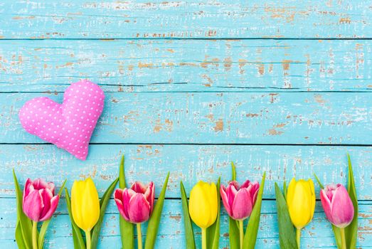 Romantic heart and tulips flowers on turquoise wooden background with copy space