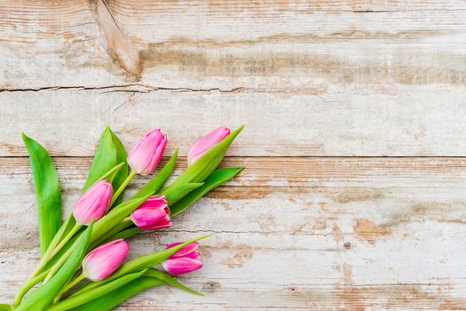 Spring flowers bouqet of pink tulips on old wood with copy space
