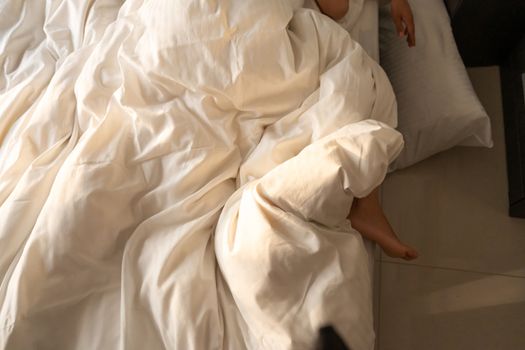 The foot of a sleeping girl in the morning hangs down the bed. Spy photo. Deep sleep