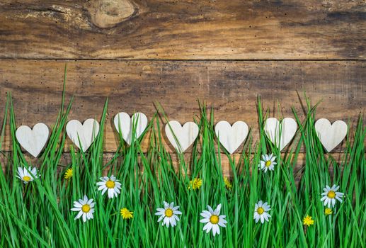 Many hearts border on wooden background with beautiful blooming meadow