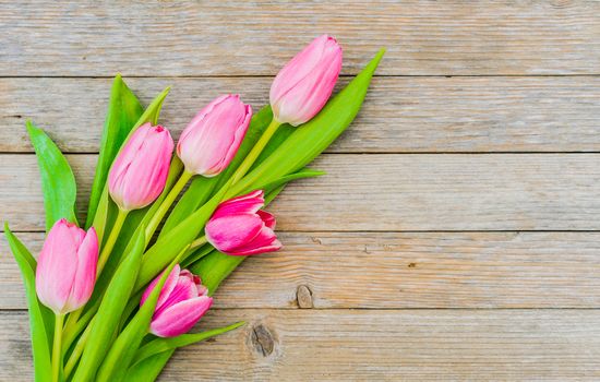 Bouquet of tulips on wooden table, top view with copy space