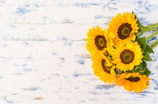 Bouquet of yellow sunflowers on rustic wooden background with copy space