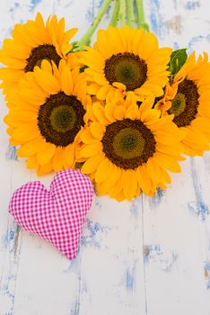 Bouquet of sunflowers with pink heart on wooden background with copy space