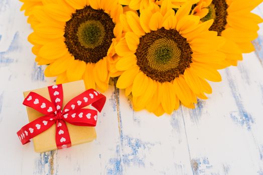 Beautiful yellow sunflowers bouquet with gift box on wooden background and copy space
