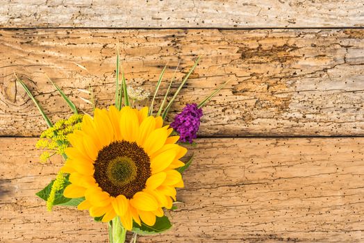 Beautiful bouquet of flowers with sunflower on old wooden background with copy spae