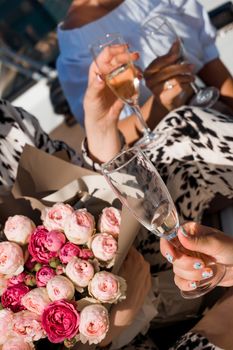 Women celebrate. Girl holds a bouquet of roses and glasses with champagne. Close up