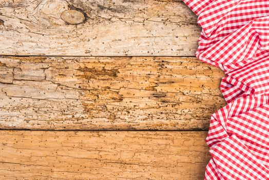 Red checked table cloth on old rustic wood background with copy space