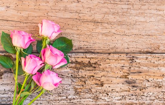 Romantic bunch of pink roses on old rustic wooden background with copy space