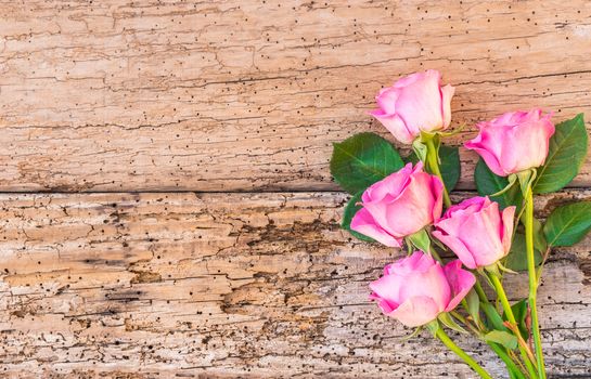 Romantic bouquet of pink roses on old wooden background with copy space