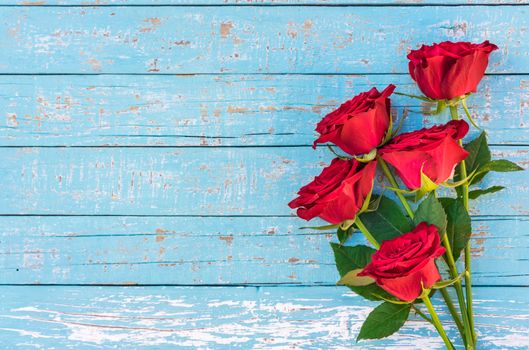 Romantic bunch of red rose flowers on blue wood background with copy space