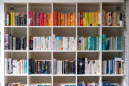 Blurred image of white wooden bookcase filled with books in a UK home setting